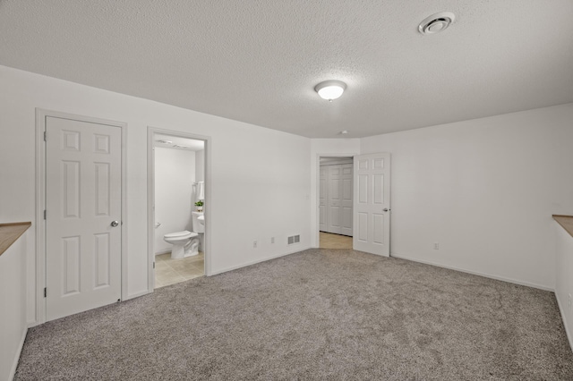 unfurnished bedroom with carpet floors, visible vents, baseboards, connected bathroom, and a textured ceiling