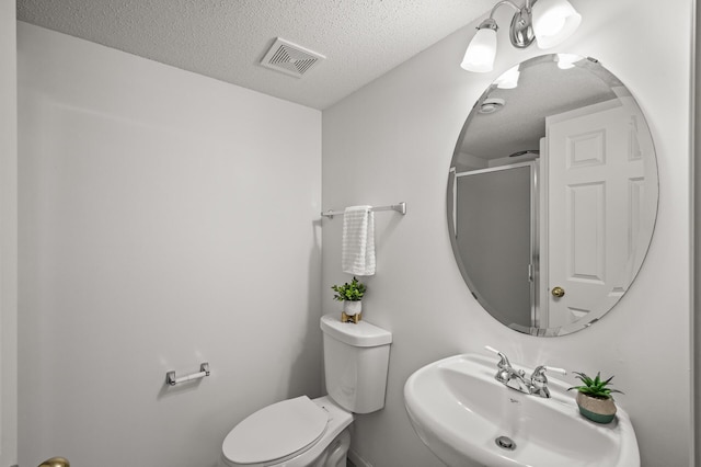 full bath featuring visible vents, toilet, a textured ceiling, an enclosed shower, and a sink