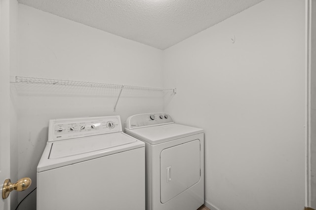 clothes washing area featuring independent washer and dryer, a textured ceiling, and laundry area