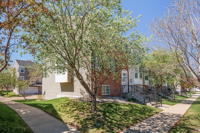 view of property hidden behind natural elements with brick siding, a residential view, and a front lawn