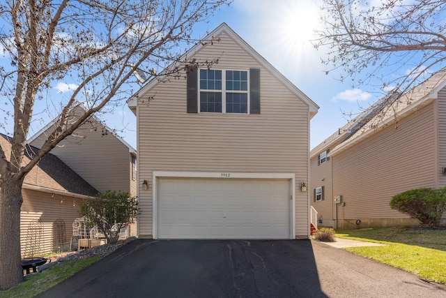 traditional-style home featuring an attached garage and aphalt driveway