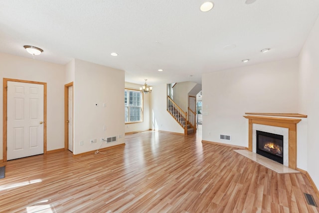 unfurnished living room featuring a chandelier, visible vents, and light wood finished floors