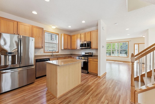 kitchen with appliances with stainless steel finishes, a sink, light wood finished floors, a center island, and recessed lighting