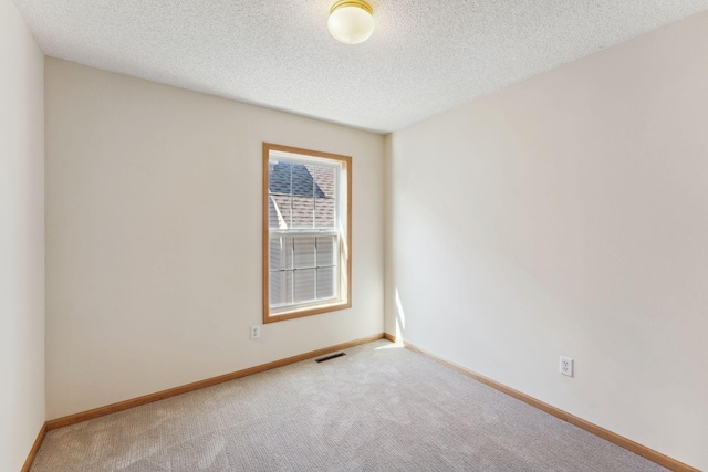 carpeted empty room featuring visible vents, a textured ceiling, and baseboards