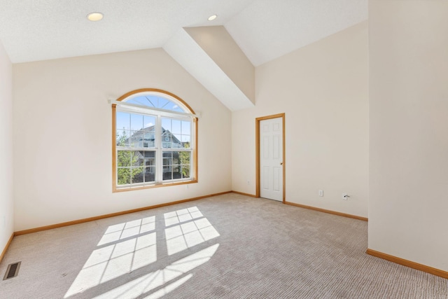 spare room featuring baseboards, visible vents, light carpet, and vaulted ceiling