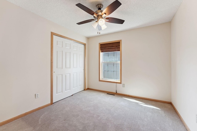 unfurnished bedroom with a textured ceiling, visible vents, baseboards, a closet, and carpet