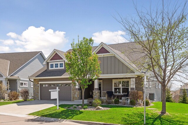 craftsman-style home featuring a porch, board and batten siding, driveway, a front yard, and stone siding