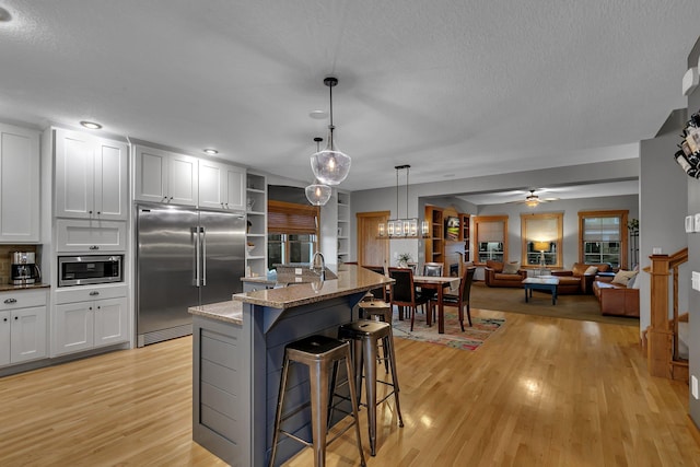 912 21st Ave N, Sartell, MN 56377 - kitchen featuring open shelves, light stone counters, built in appliances, a kitchen breakfast bar, and light wood-style flooring