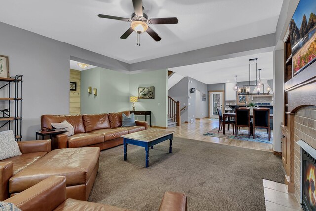 912 21st Ave N, Sartell, MN 56377 - living area featuring stairs, baseboards, light colored carpet, a fireplace with flush hearth, and ceiling fan with notable chandelier