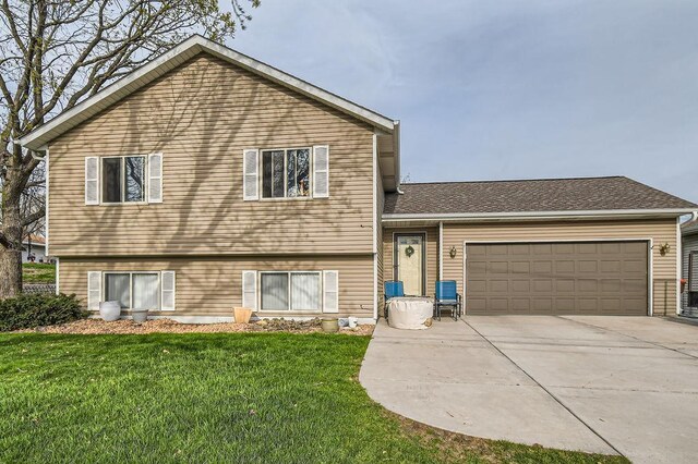 split level home with a garage, a front yard, and concrete driveway