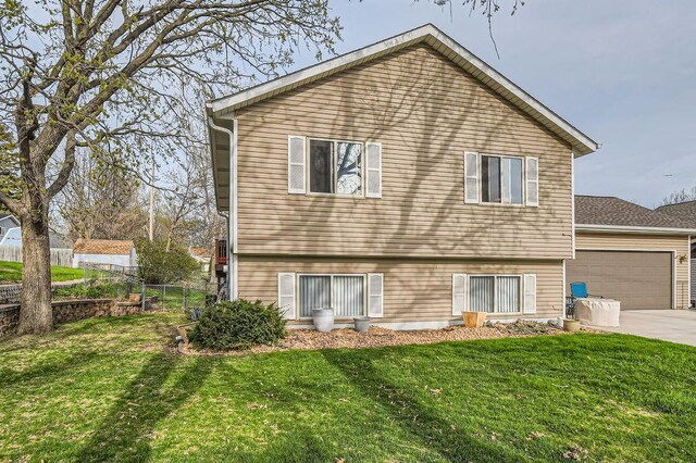 back of house featuring a lawn, fence, driveway, and a garage