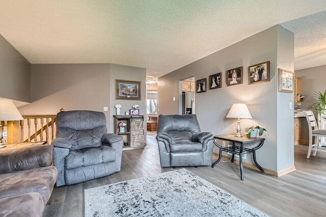 living room with a textured ceiling, baseboards, and wood finished floors