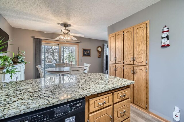kitchen with light stone counters, light wood-style floors, a textured ceiling, black dishwasher, and a ceiling fan
