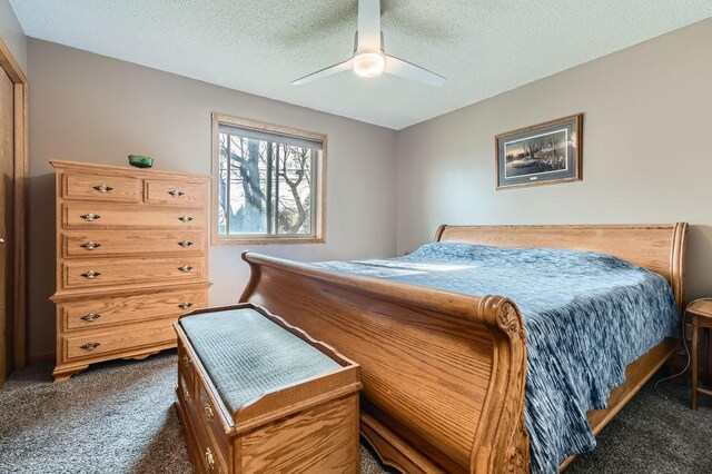 bedroom with a textured ceiling, ceiling fan, and dark carpet