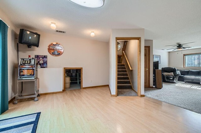 living room with visible vents, stairs, ceiling fan, and wood finished floors