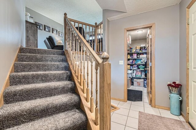 stairway with a textured ceiling and tile patterned flooring
