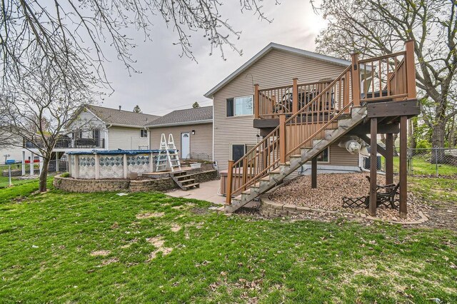 back of house with fence, a deck, a fenced in pool, a lawn, and stairway