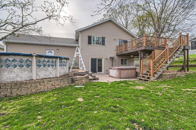 back of property featuring a yard, a deck, a hot tub, and stairway