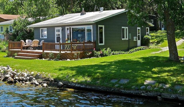 back of house featuring a lawn and a deck with water view