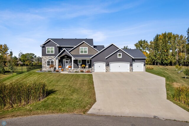 craftsman-style home with fence, a front yard, stone siding, an attached garage, and driveway