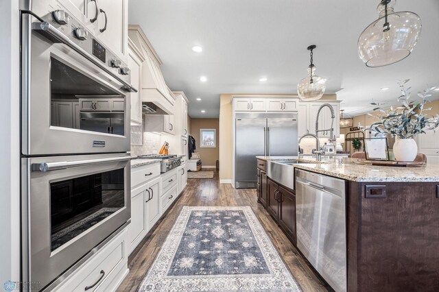 kitchen featuring dark wood-style flooring, a kitchen island with sink, dark brown cabinetry, recessed lighting, and stainless steel appliances