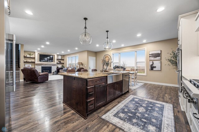 kitchen featuring stainless steel dishwasher, a sink, a wealth of natural light, and dark brown cabinets