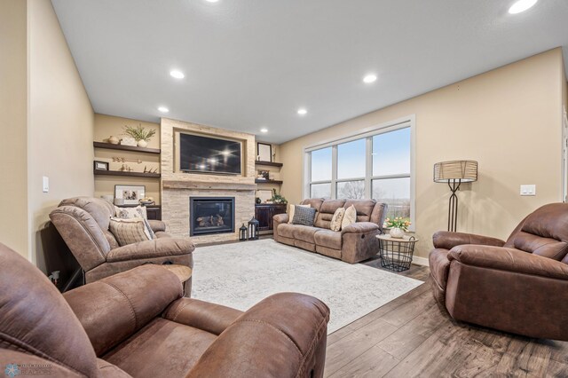 living area featuring a large fireplace, baseboards, recessed lighting, and wood finished floors