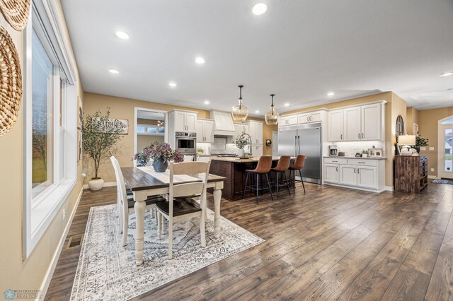dining room featuring dark wood-type flooring, recessed lighting, baseboards, and a wealth of natural light