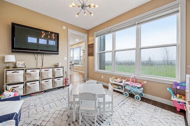 rec room featuring an inviting chandelier, baseboards, and wood finished floors
