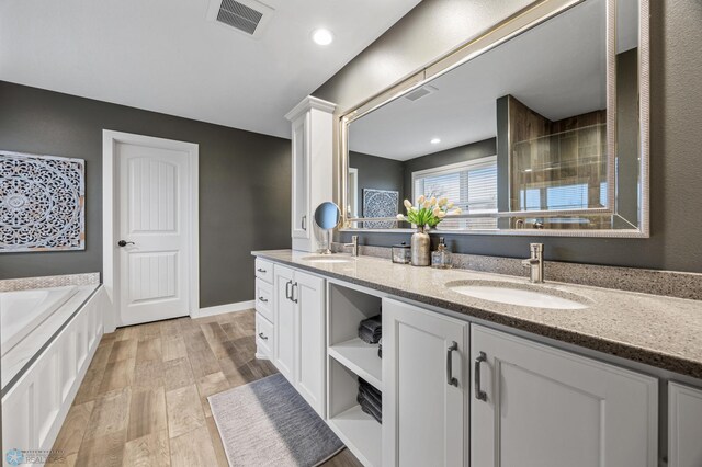 full bath featuring a sink, a bath, double vanity, and visible vents