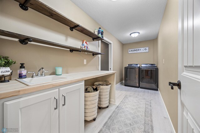 washroom with baseboards, a sink, light wood-style flooring, and washer and dryer