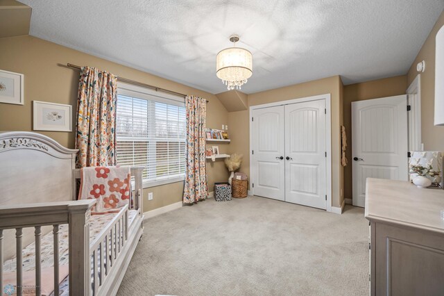 bedroom with baseboards, a closet, a textured ceiling, and light colored carpet