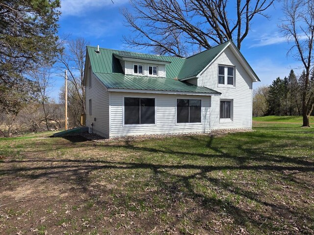 rear view of property with a lawn and metal roof