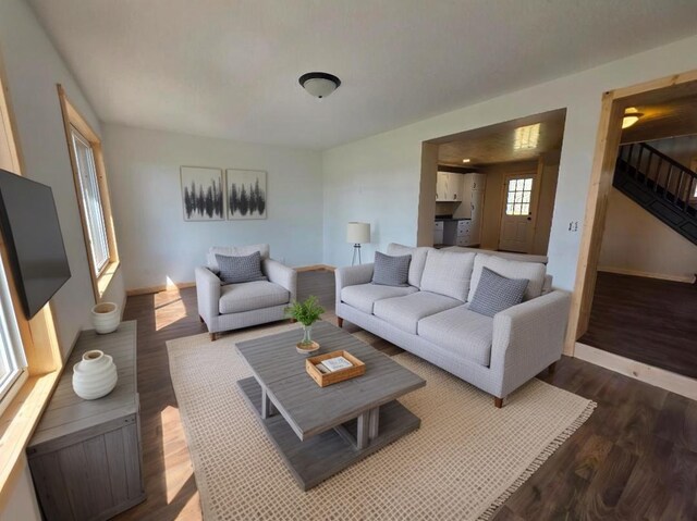living room featuring baseboards, dark wood-style flooring, and stairs