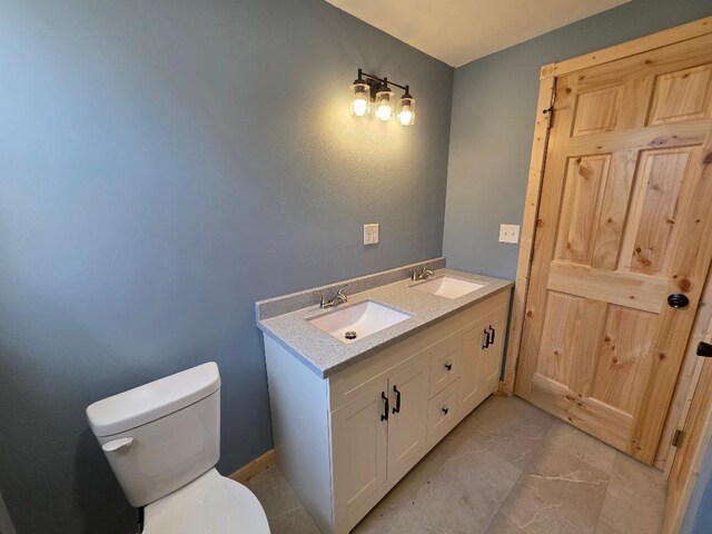bathroom featuring a sink, toilet, double vanity, and marble finish floor