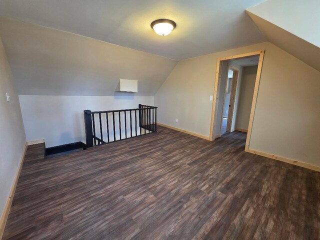 additional living space featuring baseboards, dark wood finished floors, and vaulted ceiling