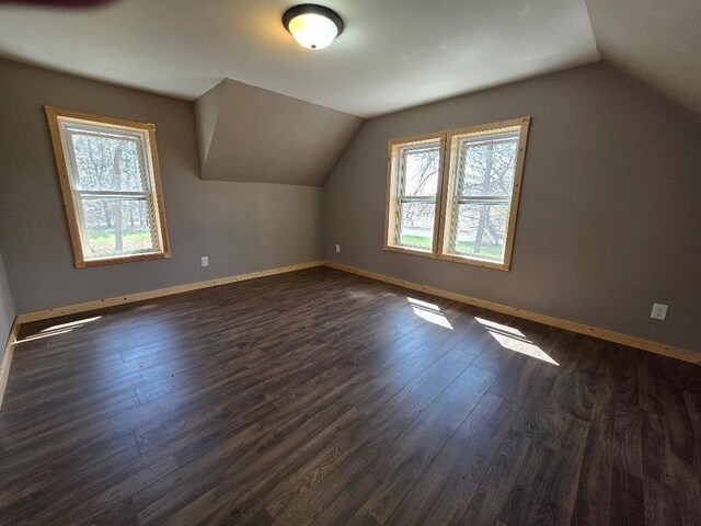 bonus room with dark wood-style flooring, baseboards, and lofted ceiling