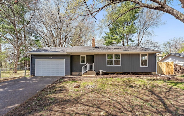 ranch-style house featuring an attached garage, aphalt driveway, fence, and a chimney