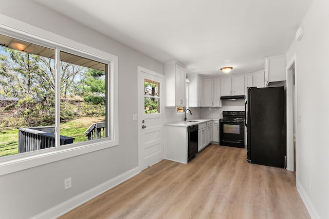 kitchen featuring decorative backsplash, light countertops, black appliances, under cabinet range hood, and white cabinetry