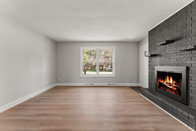 unfurnished living room with baseboards, visible vents, wood finished floors, and a fireplace