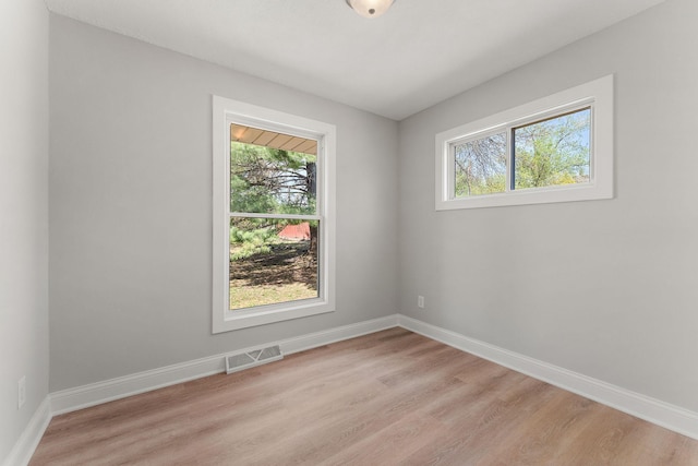 empty room featuring baseboards, visible vents, and light wood-style flooring