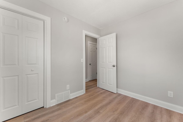 unfurnished bedroom with visible vents, baseboards, light wood finished floors, and a closet