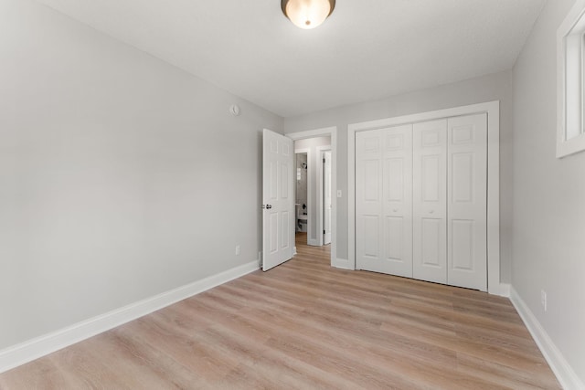 unfurnished bedroom featuring baseboards, light wood finished floors, and a closet
