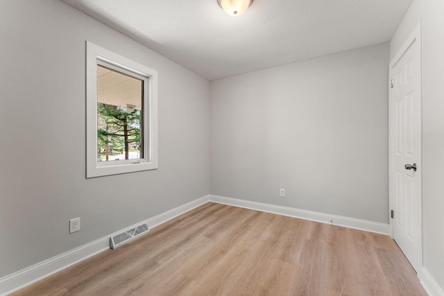 unfurnished room featuring baseboards, visible vents, and light wood-style flooring