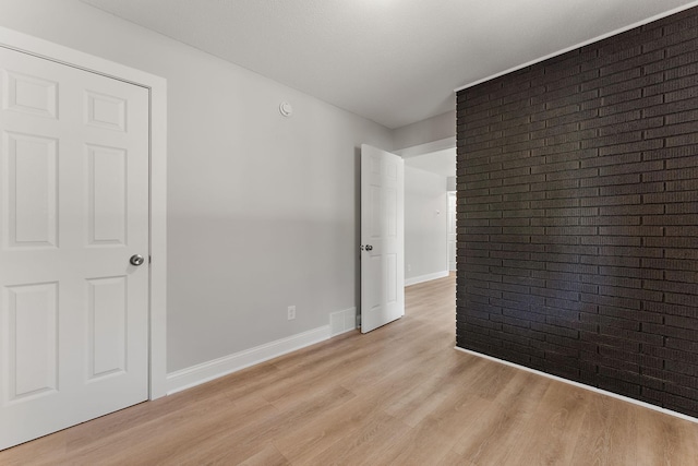 empty room with light wood-type flooring, baseboards, and visible vents