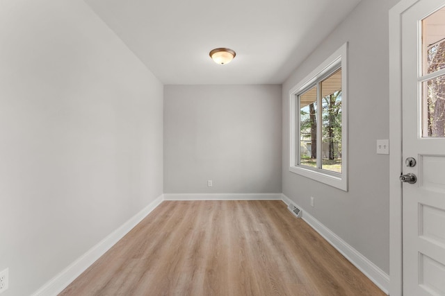 empty room with light wood-style floors, baseboards, and visible vents