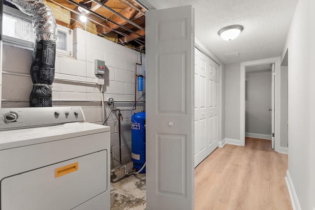 laundry area featuring concrete block wall, baseboards, and light wood finished floors