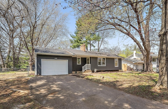 ranch-style house with fence, an attached garage, driveway, and a chimney