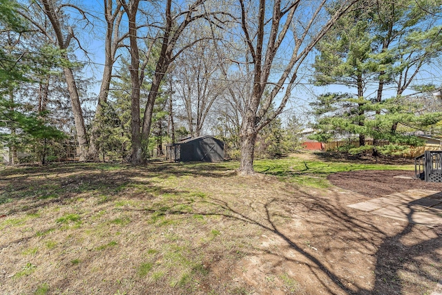 view of yard featuring an outdoor structure, fence, and a storage shed