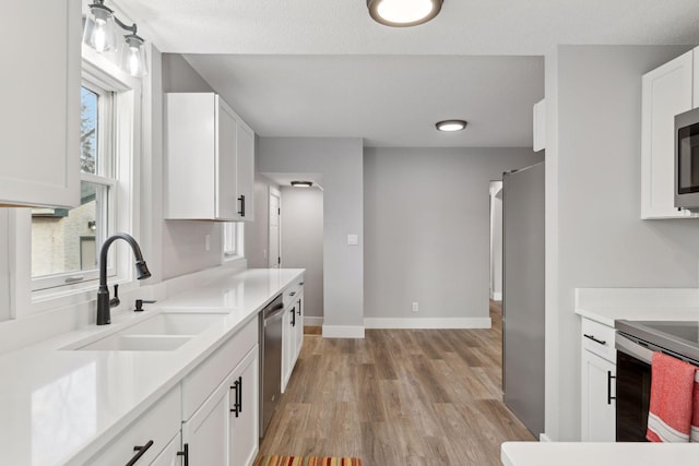 2979 Centerville Rd, Little Canada, MN 55117 - kitchen featuring light wood-type flooring, light countertops, white cabinetry, a sink, and appliances with stainless steel finishes